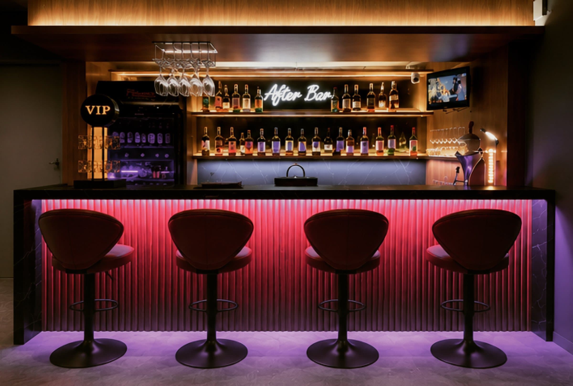 ภายในร้าน After Bar: เคาน์เตอร์ไฟสีชมพูกับเก้าอี้บาร์สี่ตัว บาร์ด้านหลัง และป้ายไฟนีออน “After Bar”